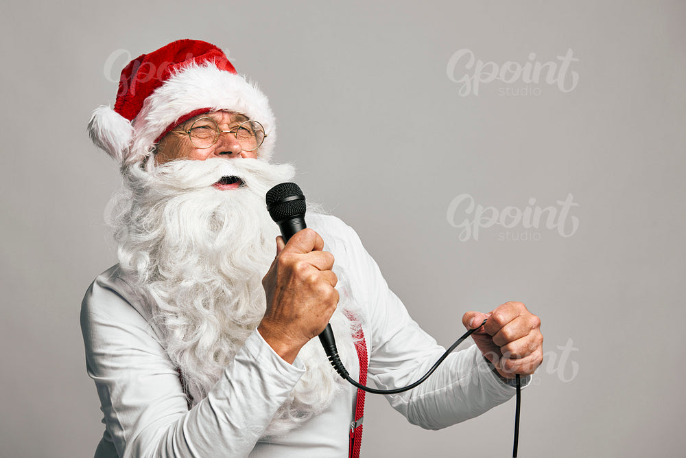 Funny caucasian Santa Claus on grey background singing Christmas songs 