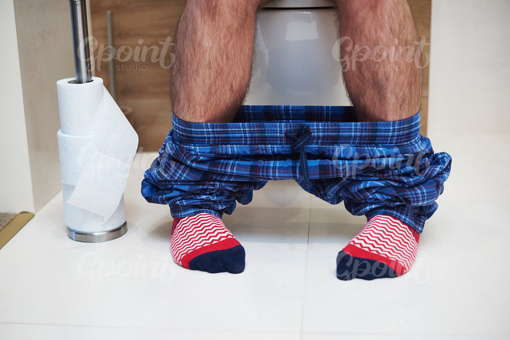 Low section of man defecating in the bathroom
