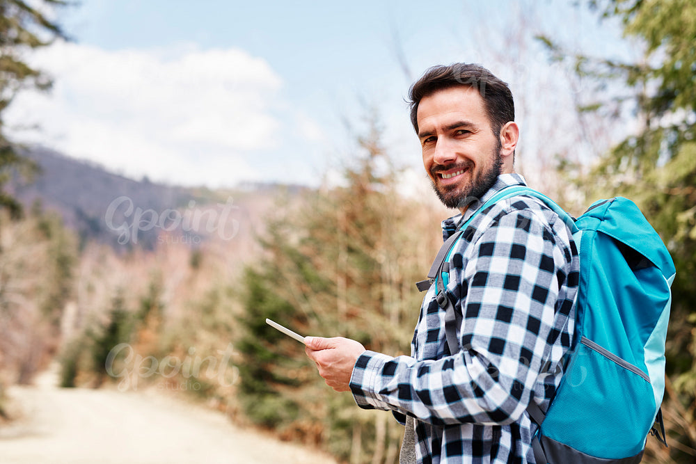 Portrait of smiling hiker using mobile phone during hiking trip