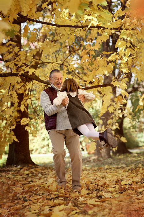 Senior man with her granddaughter have fun at the park in autumn