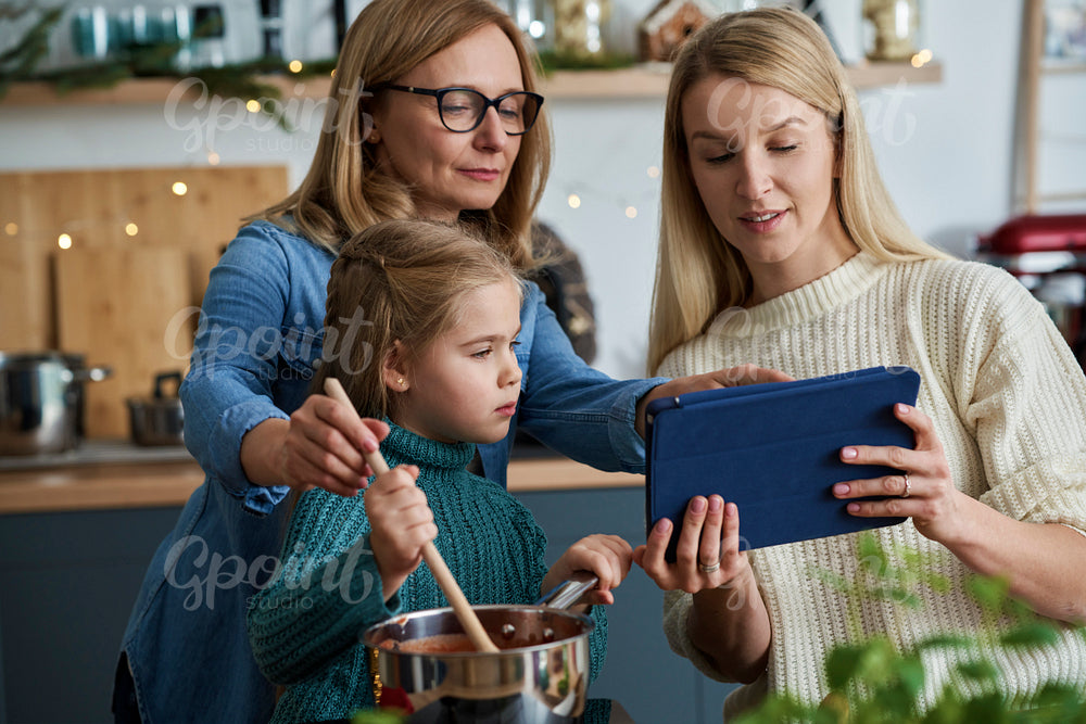 Three generations of women cooking with a tablet