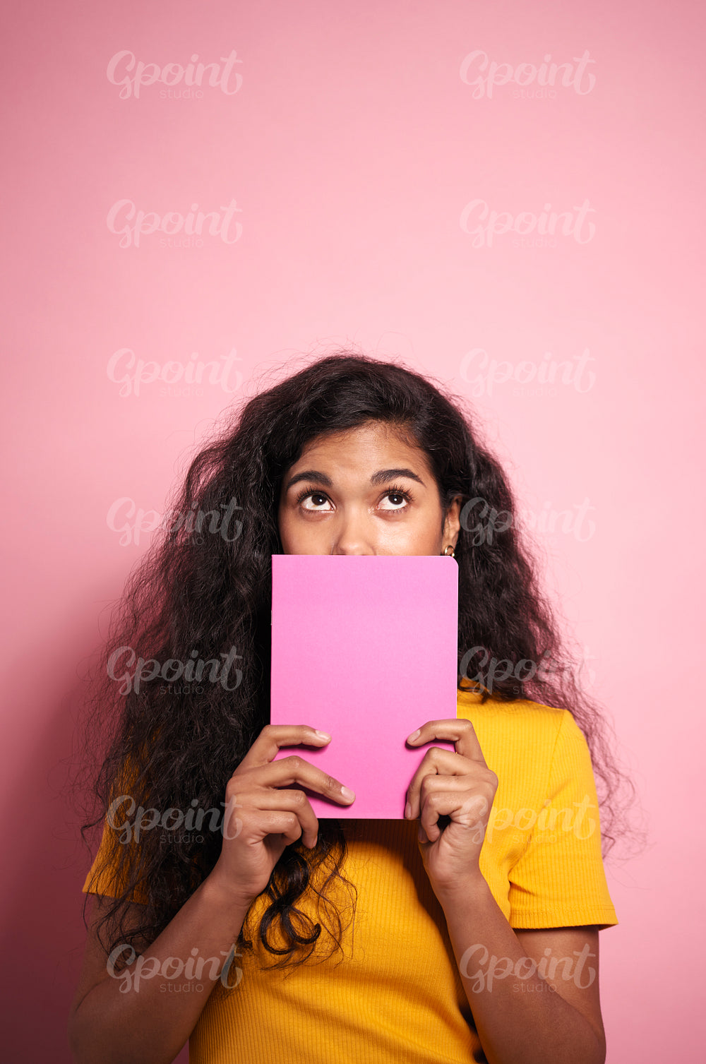 Young African woman with notebook covering her mouth.