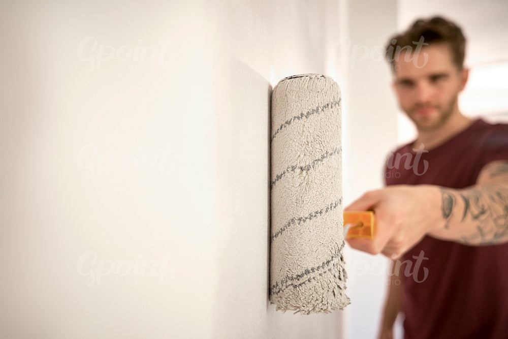Caucasian man painting wall in new house with a paint roller