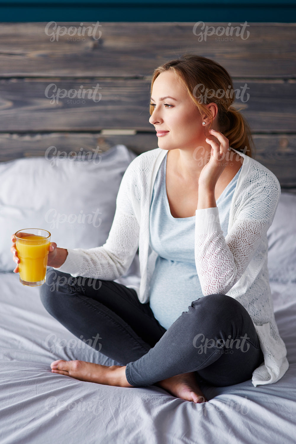 Pregnant woman with orange juice at bedroom