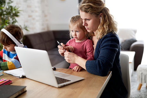 Mother during home office with little daughter on her lap