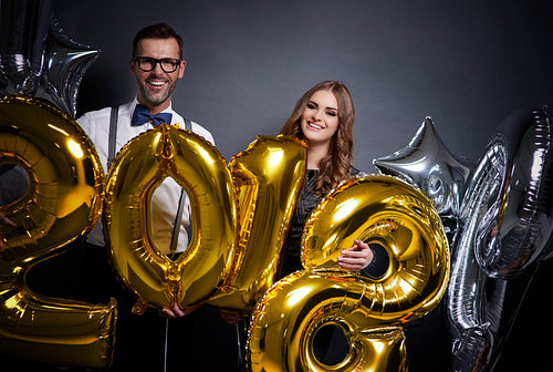 Cheerful couple holding new year's balloons