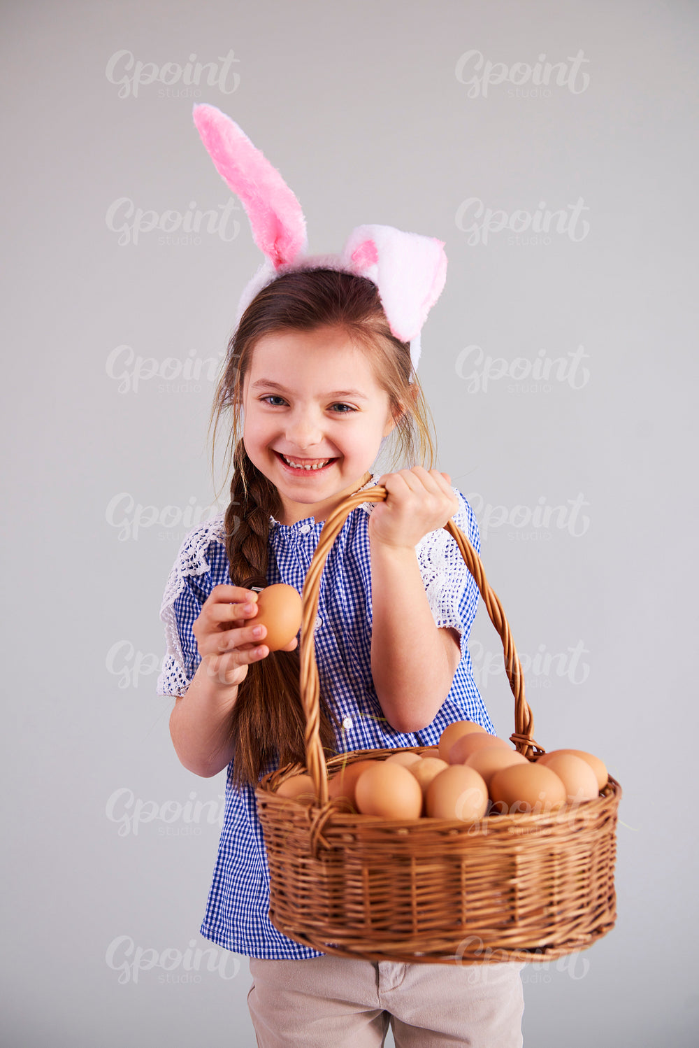 Smiling woman in rabbit costume holding a basket of eggs