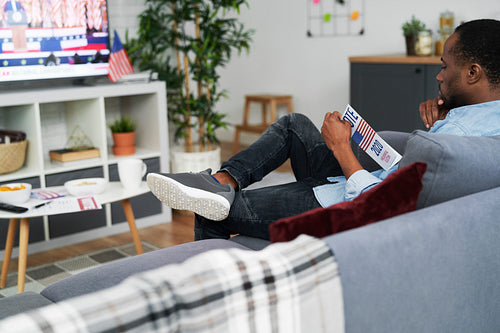 Focused man sitting on sofa and browsing information leaflet