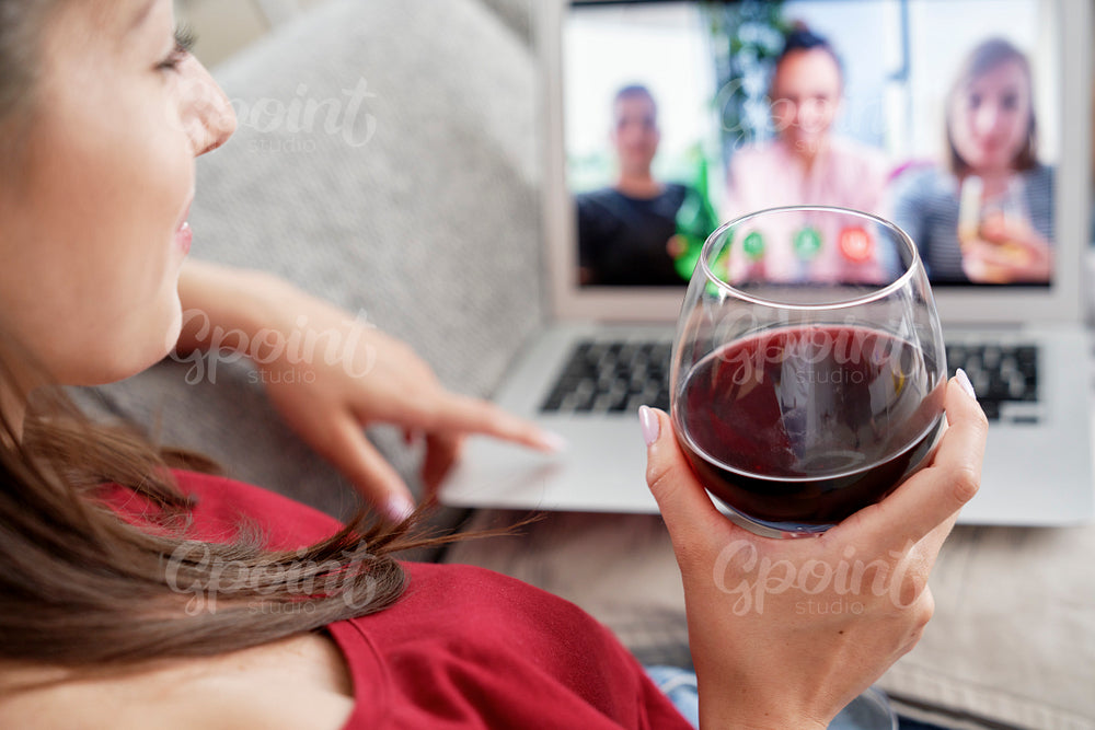 Woman drinking wine during video conference with friends