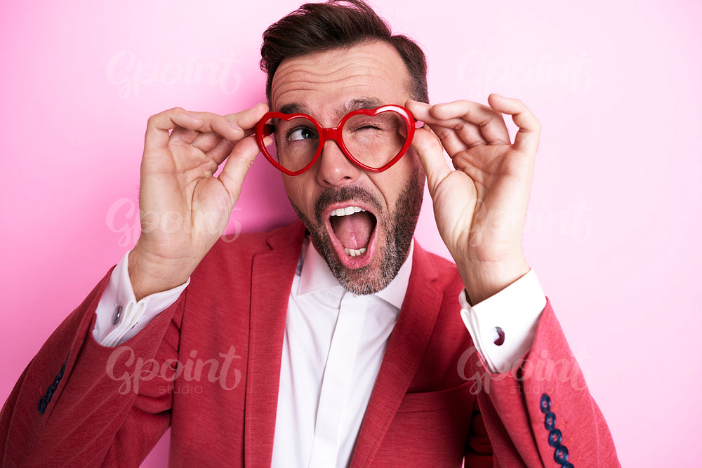 Cheerful man trying heart shape eyeglasses