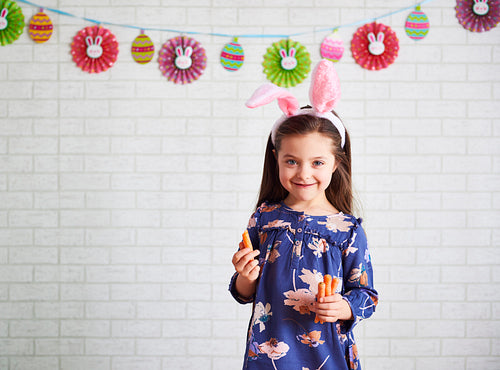 Portrait of cute girl in rabbit costume eating carrots