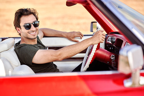 Handsome man behind the wheel of a red car