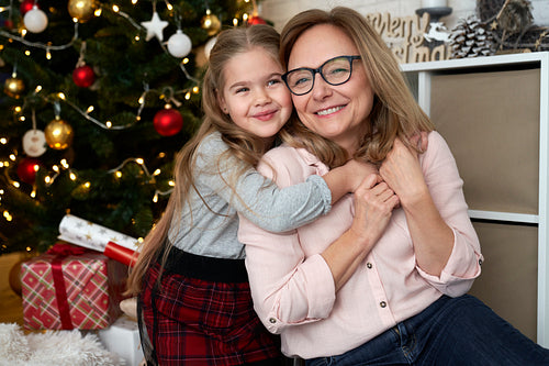 Portrait of grandmother and granddaughter embracing during Christmas