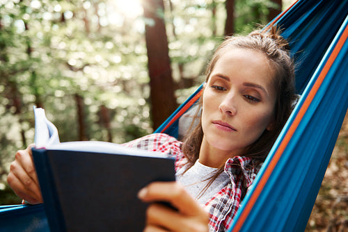 Woman relaxing on hammock and reading a book