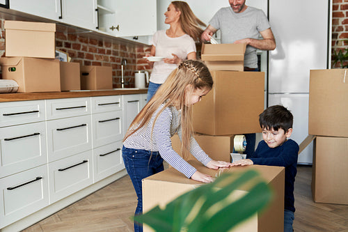 Siblings help with packing cardboard boxes for moving house