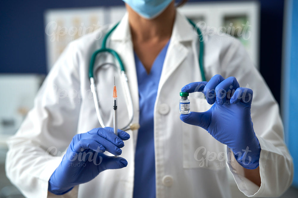 Unrecognizable doctor holding vaccine and syringe for prevention from COVID-19