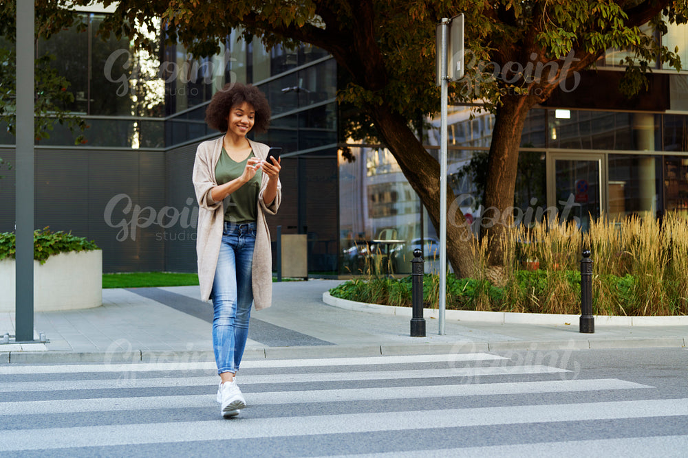 Woman with mobile phone crossing the street