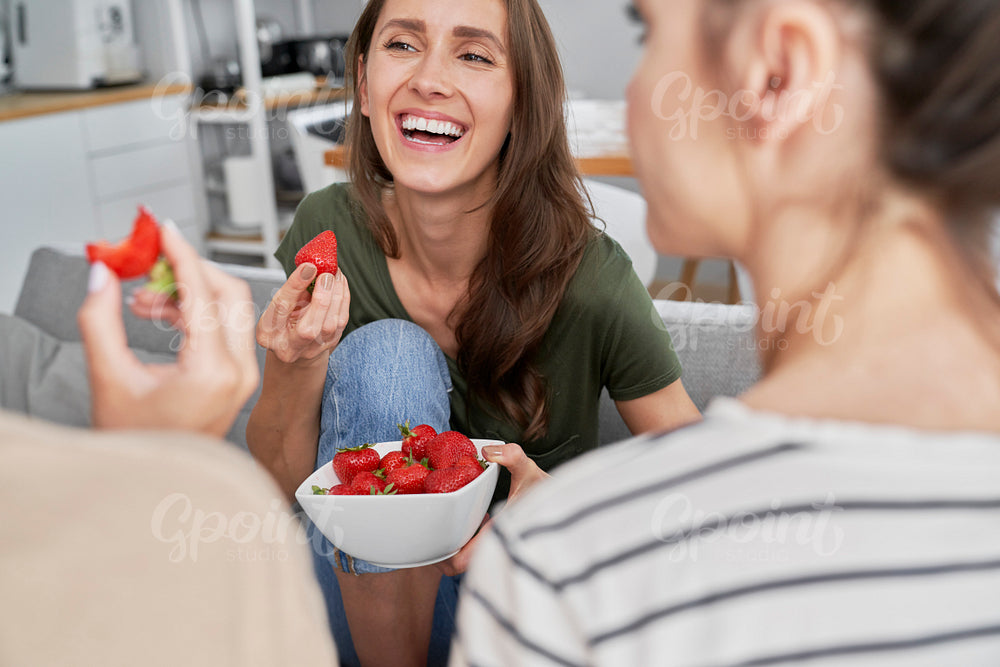 Three friends chatting and eating seasonal strawberries