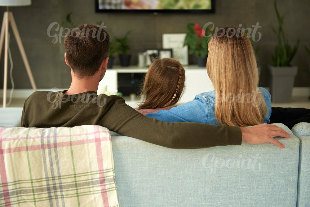 Rear view of family with one child watching tv