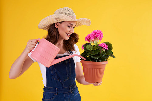 Smiling woman watering flowers in flower pot