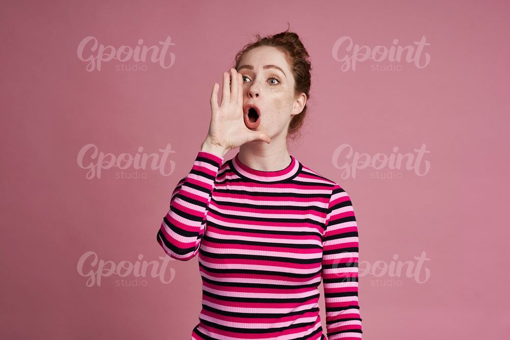 Studio shot of young woman screaming and standing on the pink background 