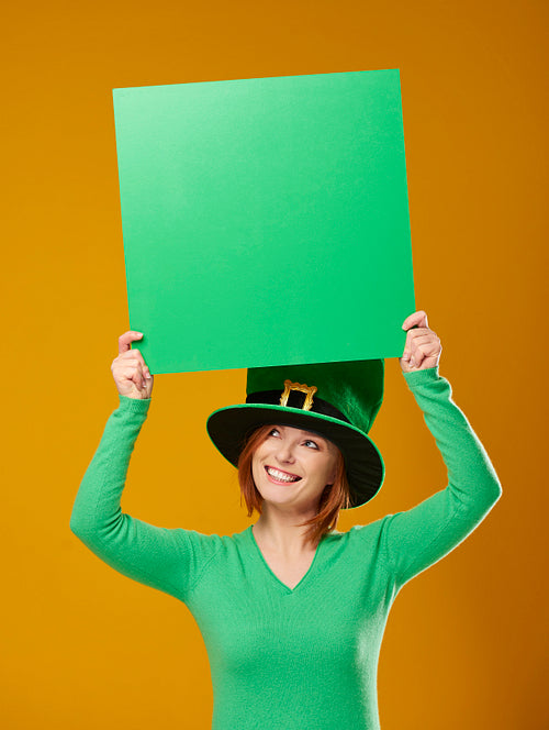 Woman with leprechaun's hat showing green banner with copy space