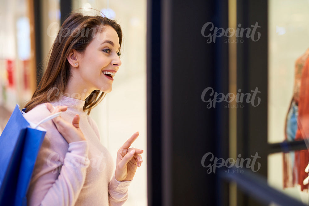 Young woman looking at shop window with clothing