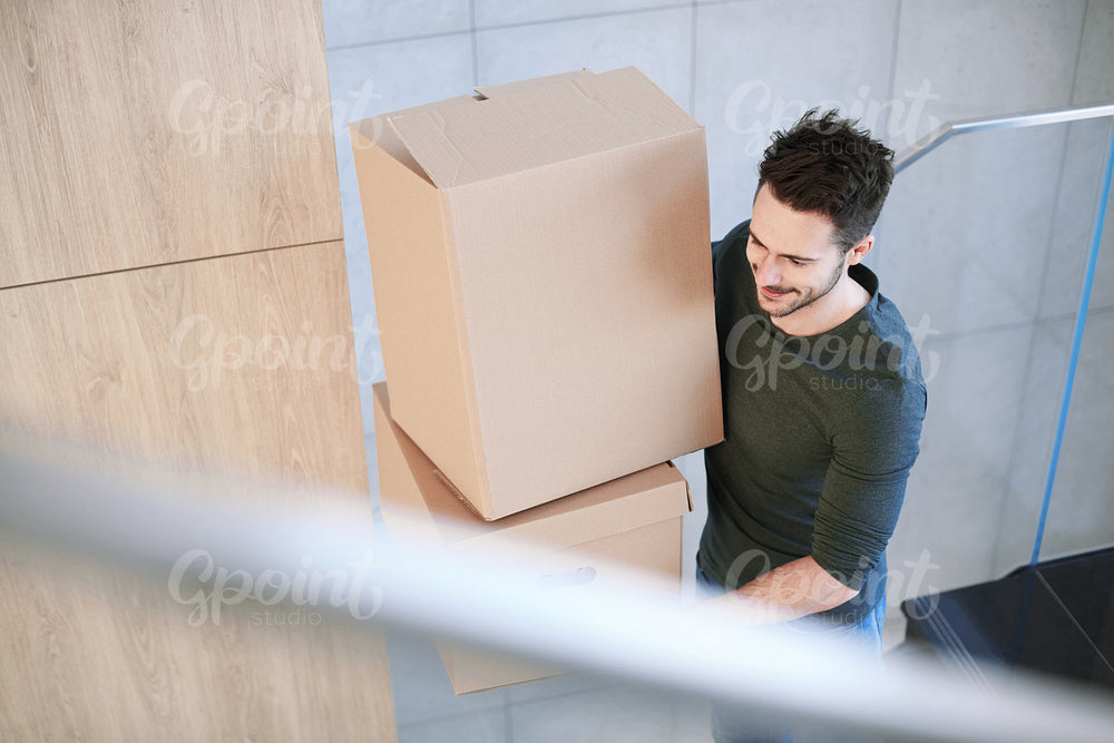 Man smiling and carrying moving box indoors