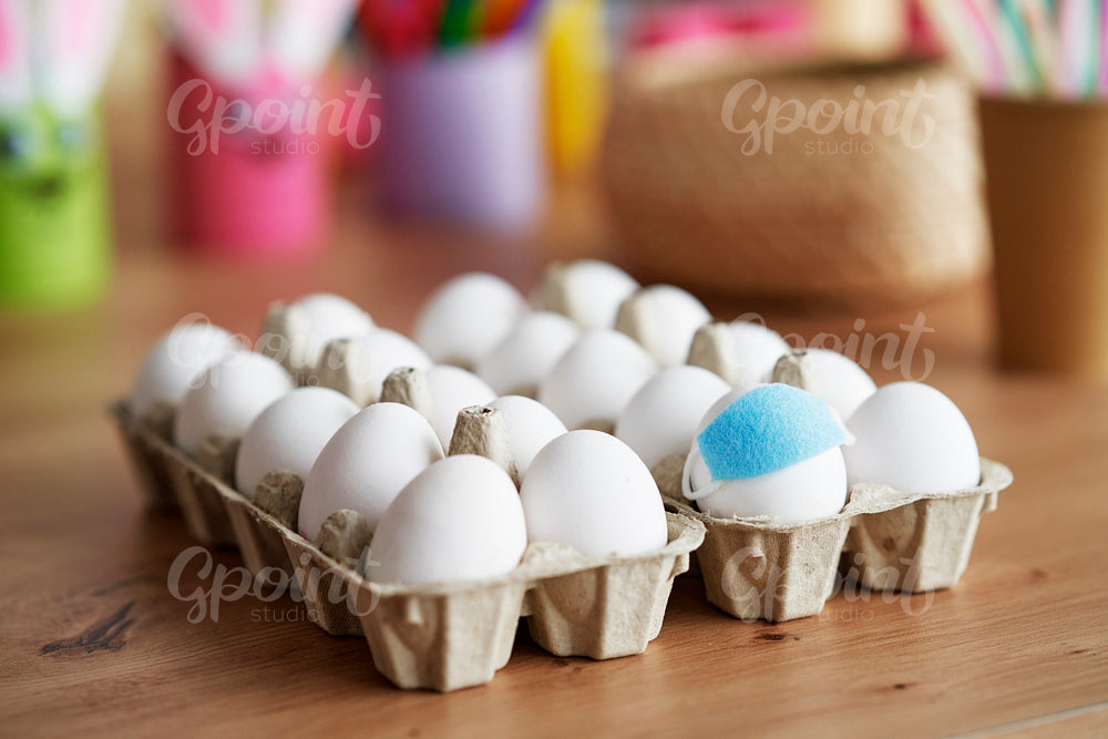 Close up eggs with face masks in a cardboard box