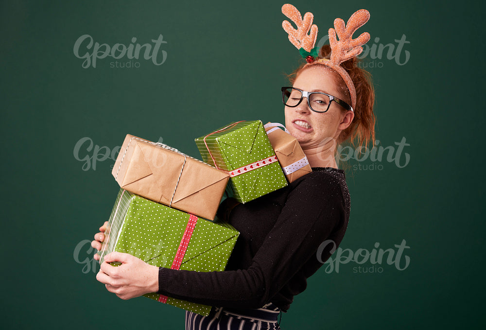 Funny woman carrying stack of christmas gifts