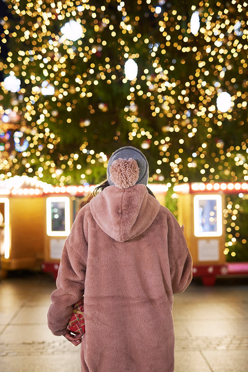 Rear view of woman standing and looking at Christmas tree