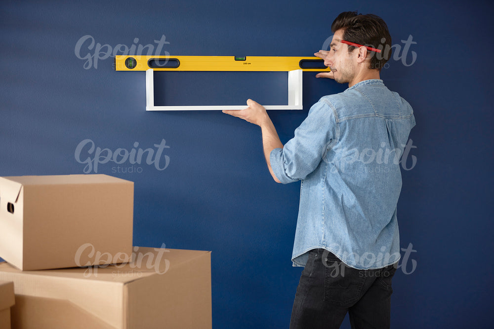 Man checking if the shelf in perfectly horizontal