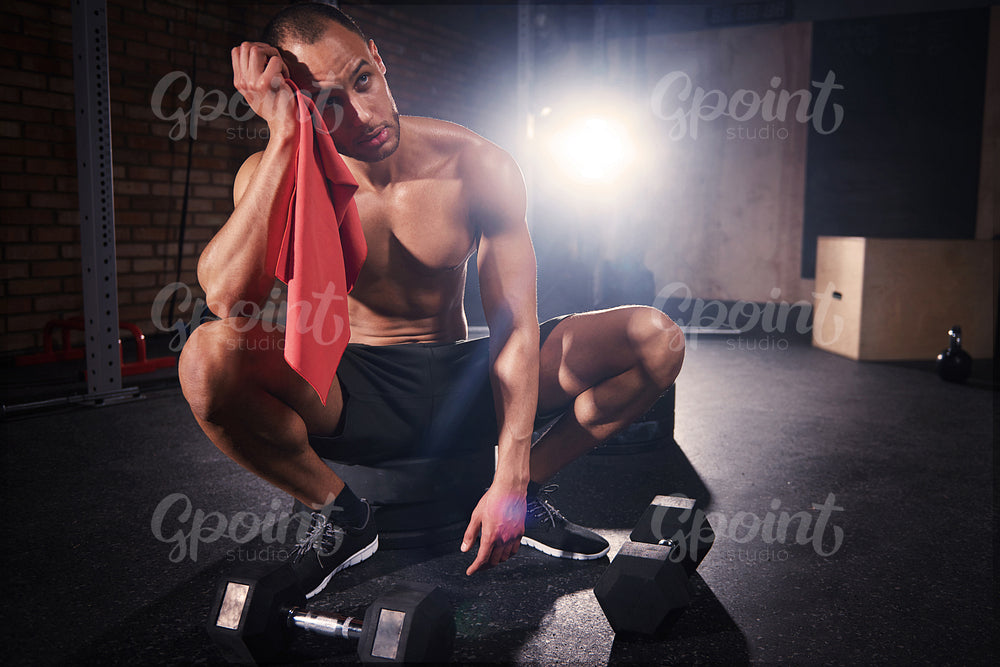 Young bodybuilder wiping sweat with towel