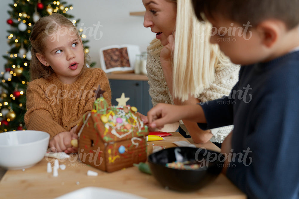 Family talking while decorating gingerbread house