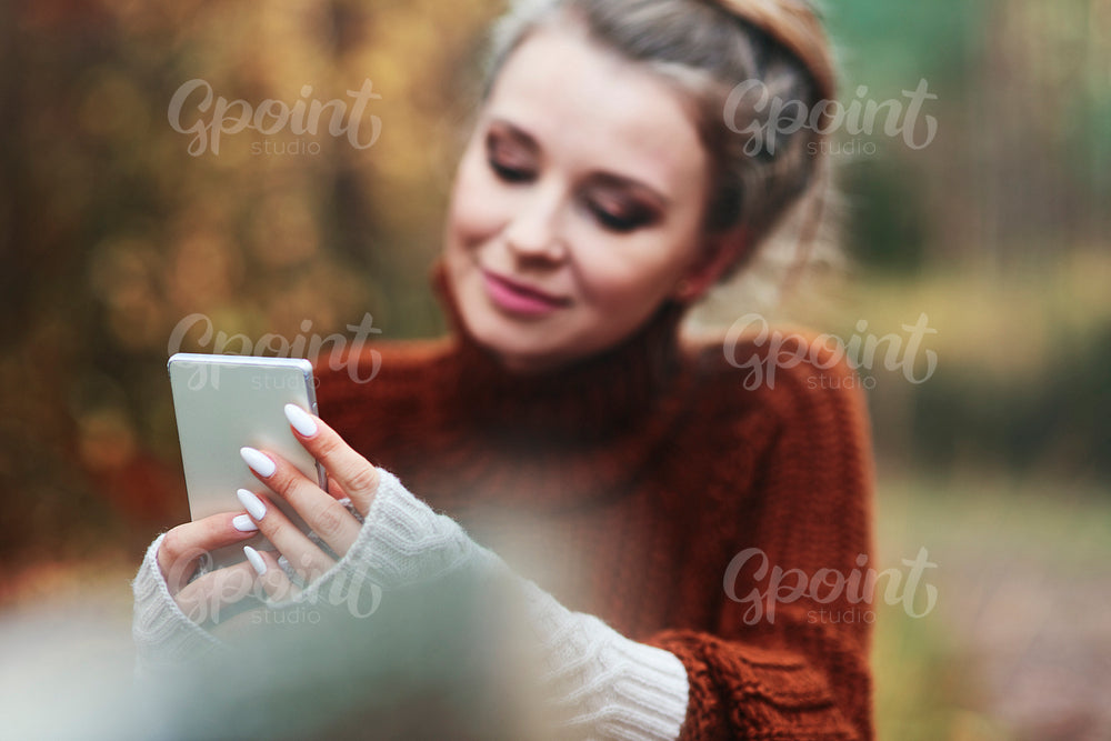 Beautiful young woman using phone in forest
