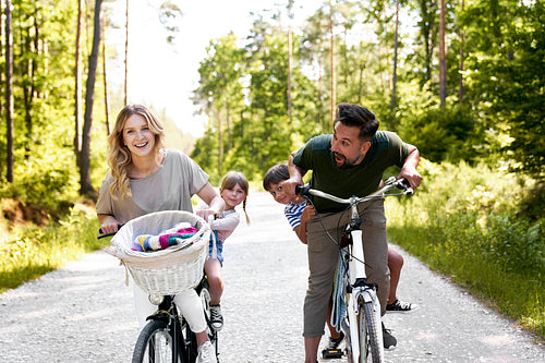 Playful family having fun on a bicycles in the woods