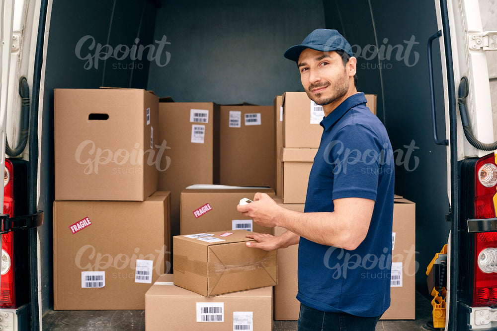 Portrait of smiling courier checking parcels in a car