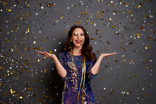 Woman holding something on her hand under shower of confetti