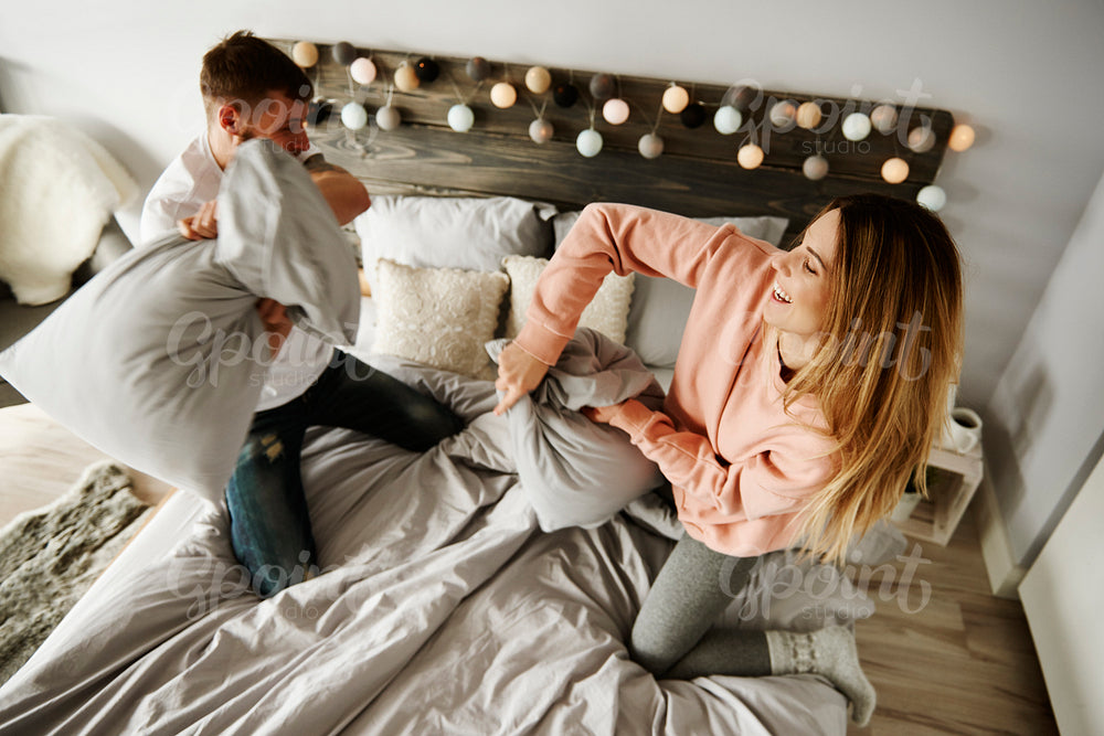 Couple fighting with pillows in bedroom