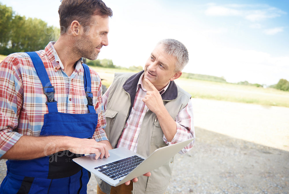 Thoughtful farmers talking over laptop