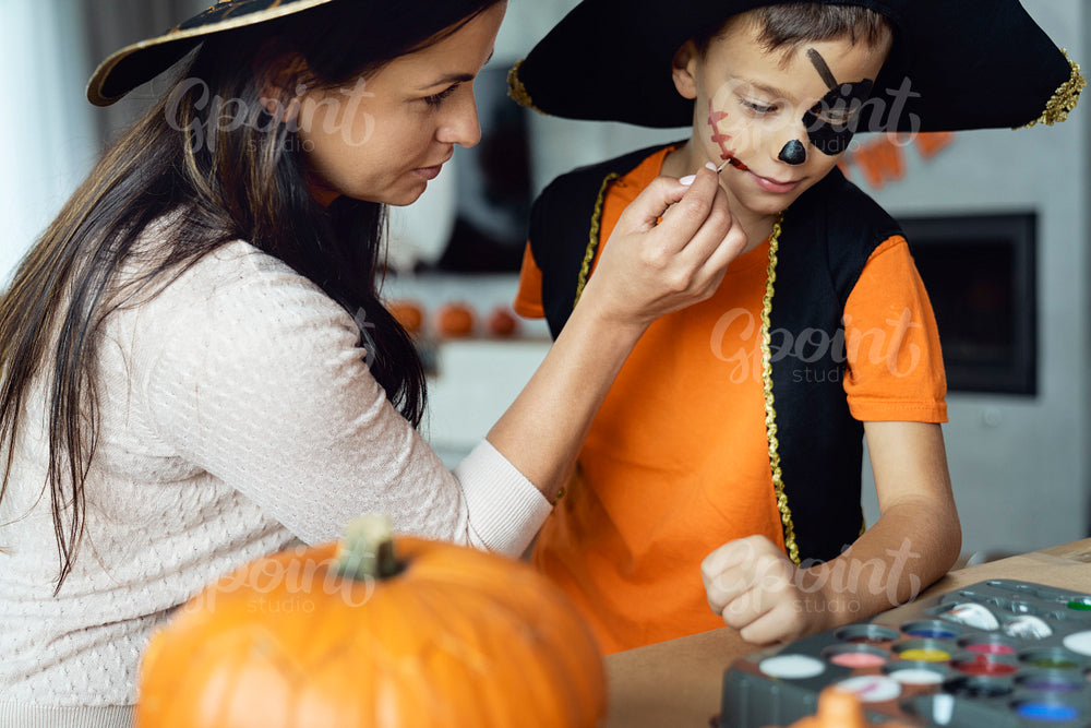 Mom painting face her son to Halloween's party 