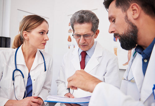 Three doctors discussing medical records in doctor’s office