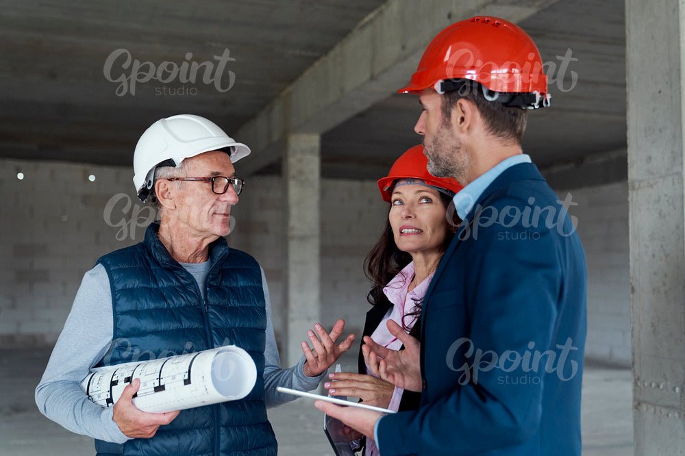 Medium shot of group of  caucasian engineers and investors discussing on construction site 