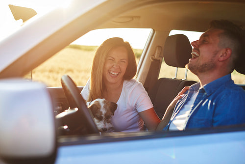 Joyful scene of young couple and dog during road trip