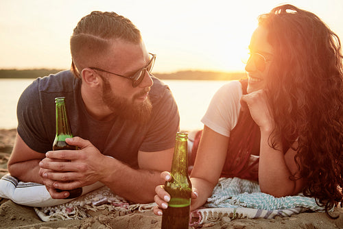 Loving couple drinking beer on the beach