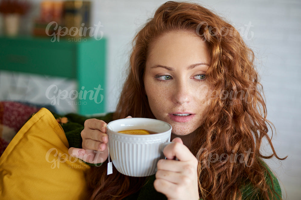 Young woman drinking tea with lemon in the living room