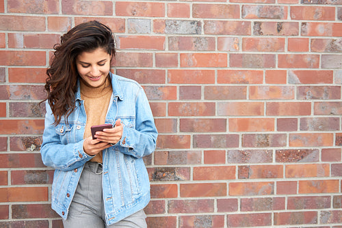 Smiling young woman with smart phone in the city