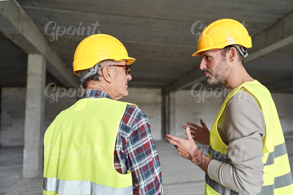 Back view of two caucasian engineers discussing on construction site  