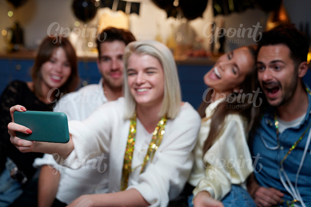 Cheerful friends taking selfie on the party