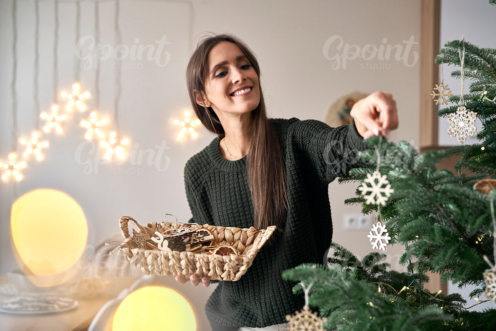 Caucasian woman decorating Christmas tree at home 